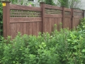 Authentic walnut wood grain vinyl fence from grand illusion manufacture maintenance free looks like wood and blends beautiful with foliage Rye NY