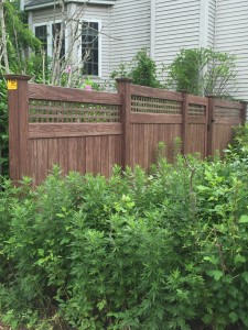 Authentic walnut wood grain vinyl fence from grand illusion manufacture maintenance free looks like wood and blends beautiful with foliage  Rye NY
